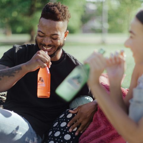 man in black and white polka dot shirt holding orange plastic cup