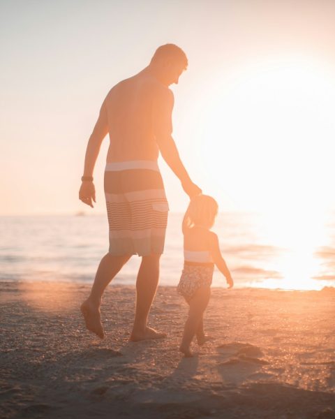 man holding girl heading towards sea