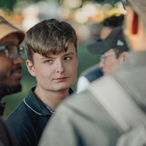 A young man looks at someone nearby.