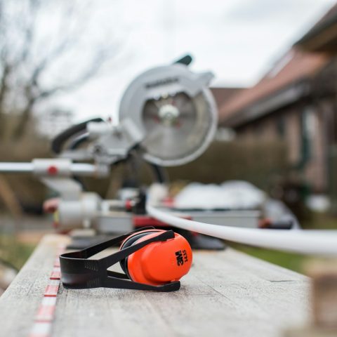 black and red 3M earmuffs beside miter saw