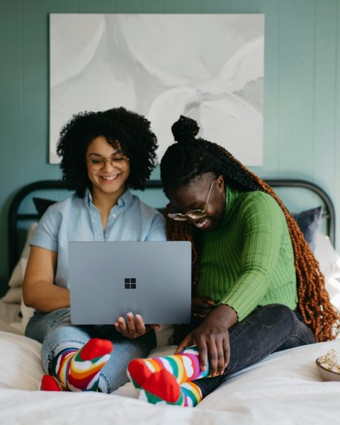 a woman sitting on a bed using a laptop