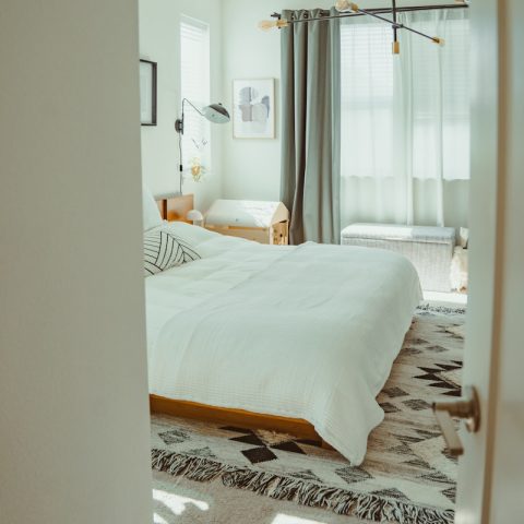 A bright, modern bedroom with a patterned rug.