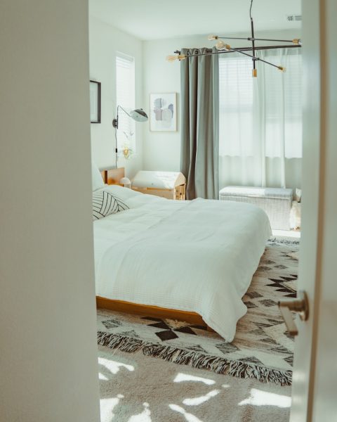 A bright, modern bedroom with a patterned rug.