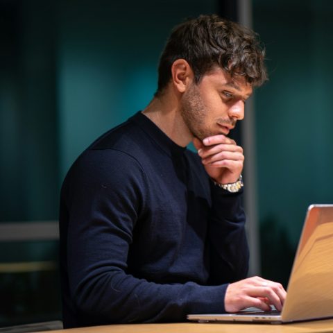 man in black long sleeve shirt sitting in front of macbook