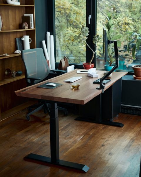 a desk with a laptop on it in front of a window