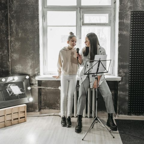 A teenager and teacher singing in a modern studio, enhancing vocal skills.
