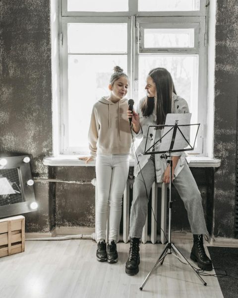 A teenager and teacher singing in a modern studio, enhancing vocal skills.
