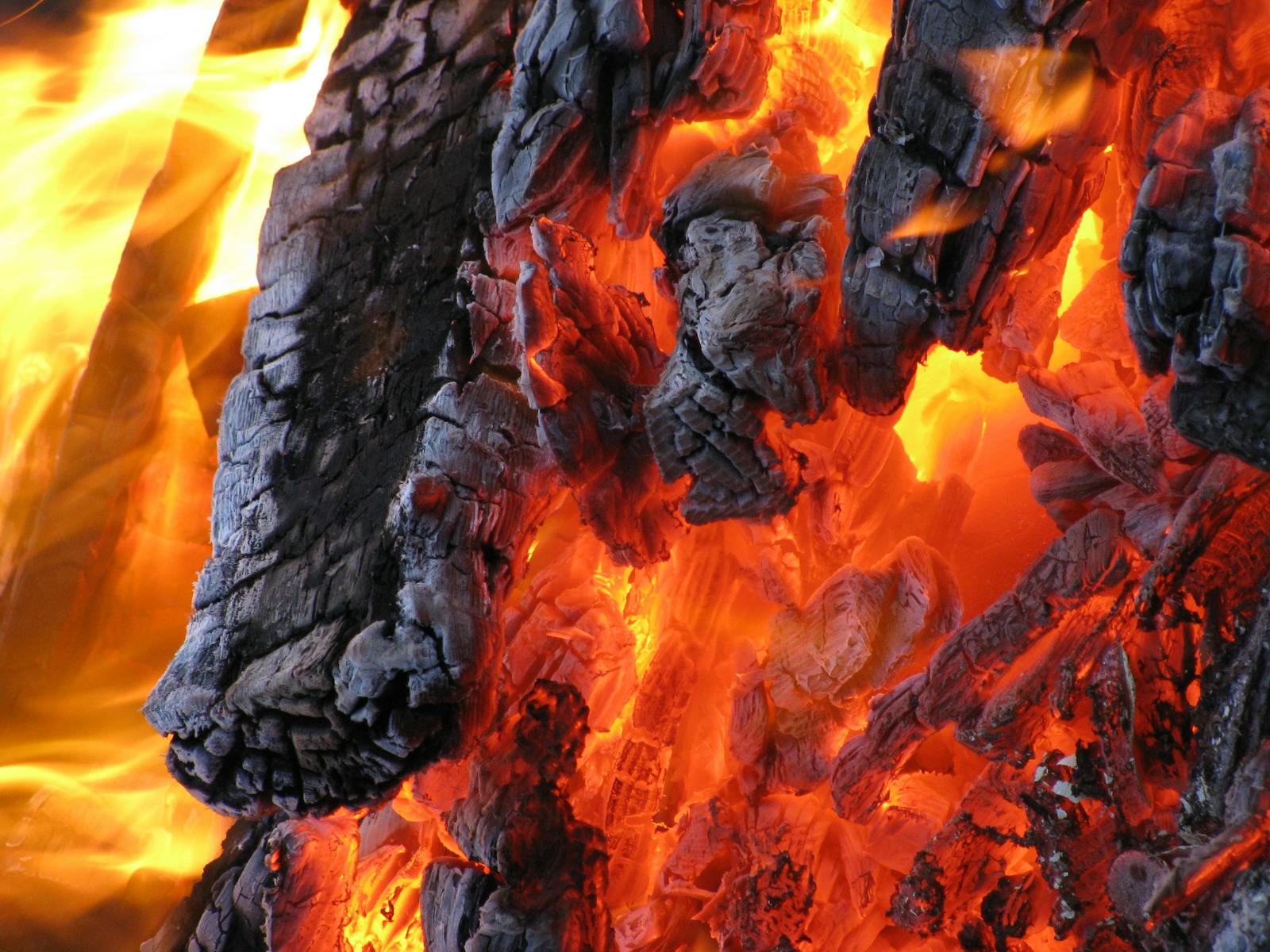 Detailed view of hot embers and flames from burning charcoal. A vibrant display of fire and heat.