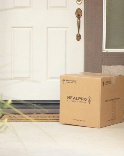 brown cardboard box beside white wooden door