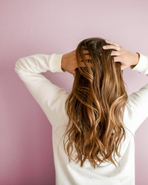 woman in white long-sleeved shirt standing in front of pink wall