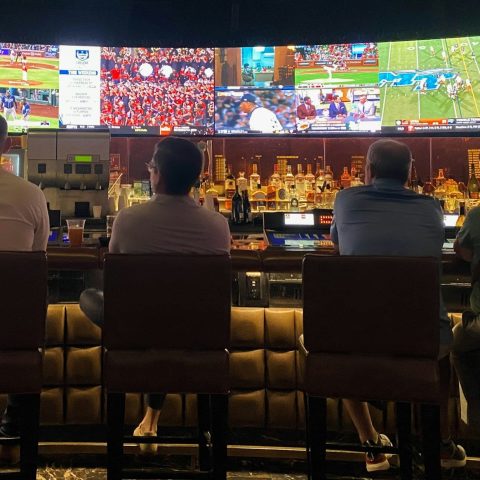 a group of people sitting at a bar watching tv