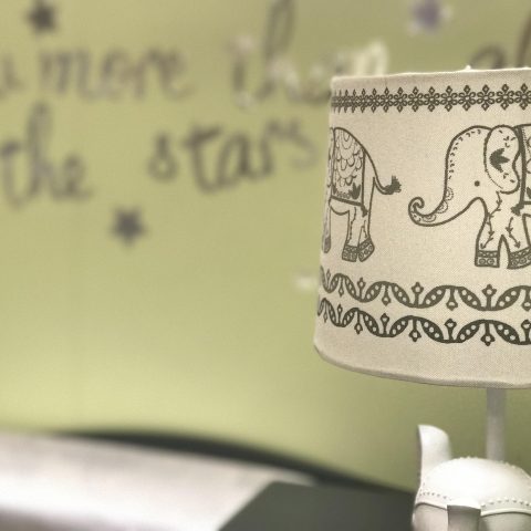 Pastelkleurige babykamer met ledikant, commode en zachte verlichting