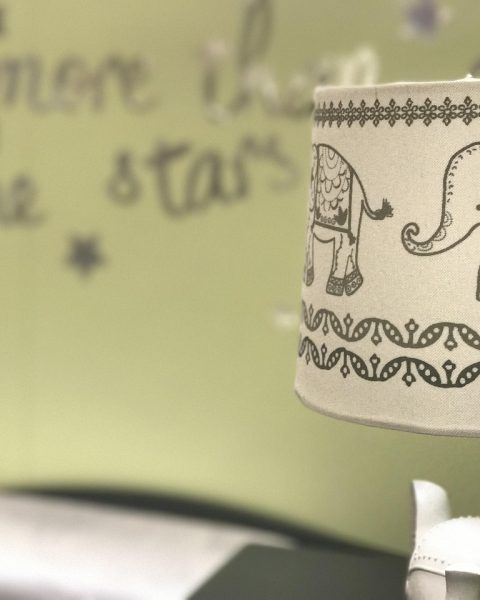 Pastelkleurige babykamer met ledikant, commode en zachte verlichting
