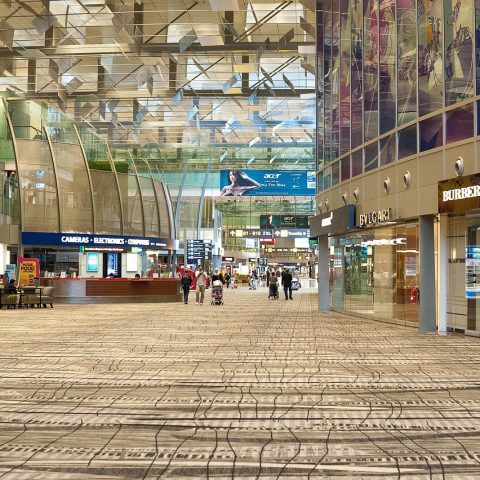 Reizigers wachten in een lichte, moderne vertrekhal op een grote Europese luchthaven