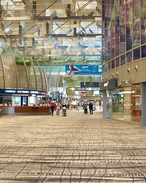 Reizigers wachten in een lichte, moderne vertrekhal op een grote Europese luchthaven