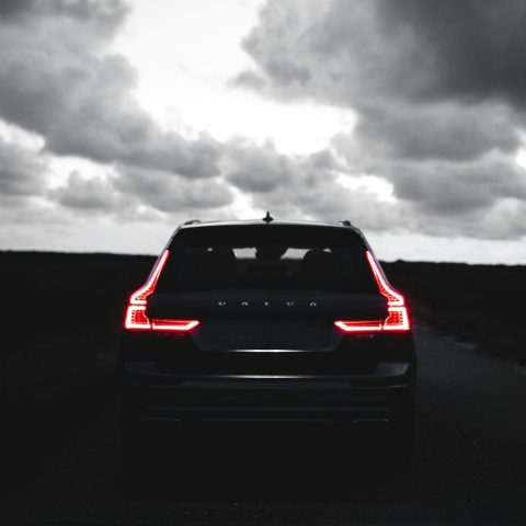 red car on black asphalt road under gray cloudy sky