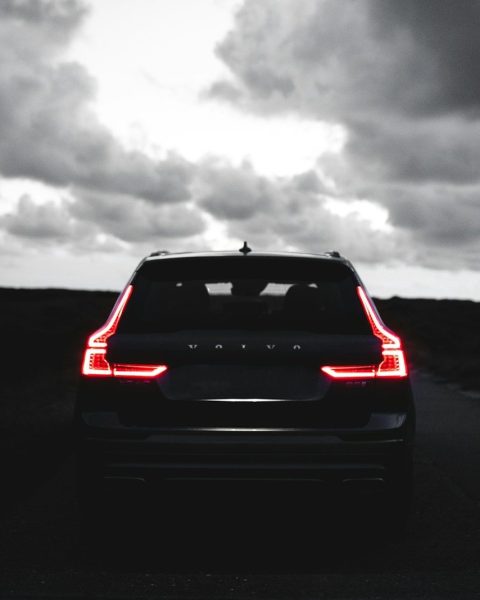 red car on black asphalt road under gray cloudy sky