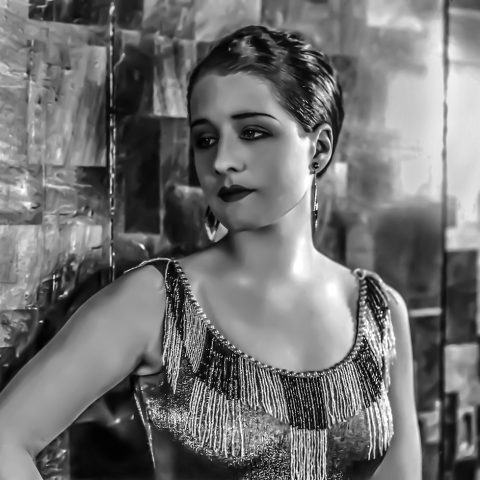 Een actrice op een filmset in een donkere, sfeervolle omgeving die doet denken aan een horrorproductie