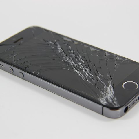 Een smartphone met een gebarsten scherm op een werkbank bij een hersteller