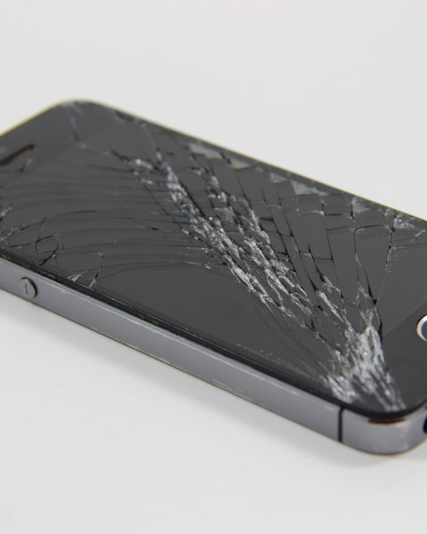 Een smartphone met een gebarsten scherm op een werkbank bij een hersteller