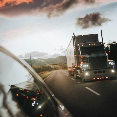 A semi truck driving on a highway under a warm orange sky