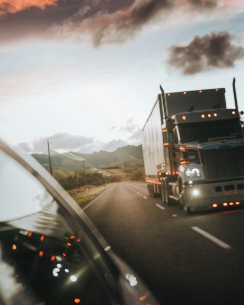 A semi truck driving on a highway under a warm orange sky
