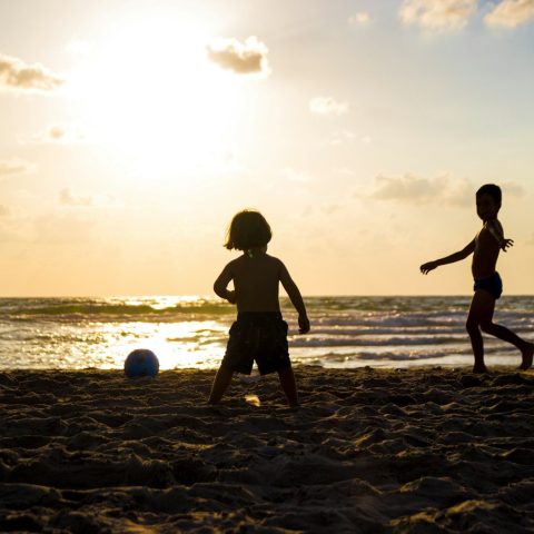 silhouette of three children on beach