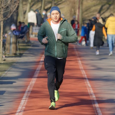 Een man loopt rustig door een park op een ochtend, als metafoor voor Ruben Van Gucht die sport gebruikt om tot rust te komen buiten zijn televisiewerk.