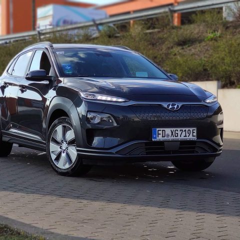 Gezin met kinderen die bagage laden in een elektrische SUV op de oprit