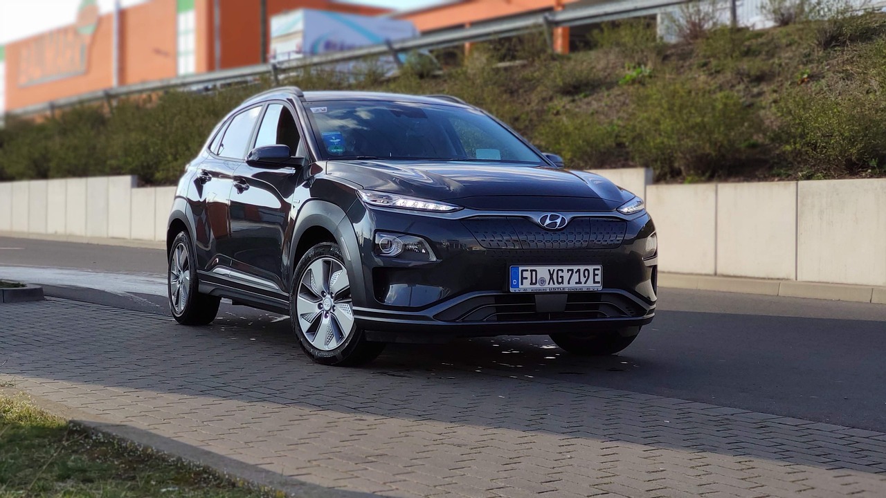 Gezin met kinderen die bagage laden in een elektrische SUV op de oprit