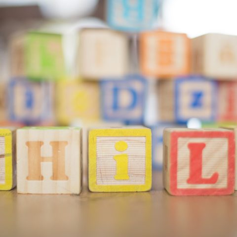 Kind speelt geconcentreerd met houten blokken op de vloer