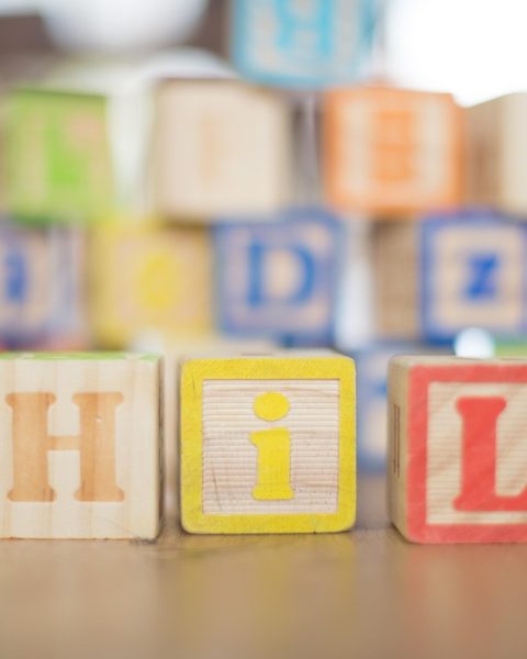 Kind speelt geconcentreerd met houten blokken op de vloer