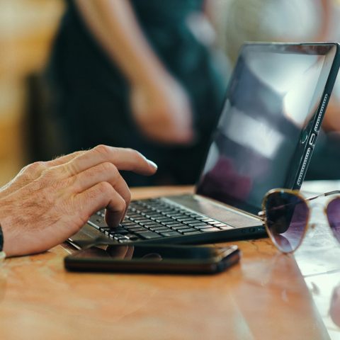 Persoon typt op een laptop toetsenbord aan een bureau