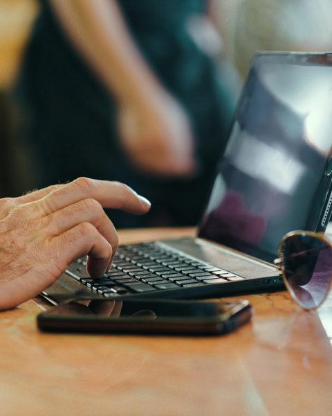 Persoon typt op een laptop toetsenbord aan een bureau