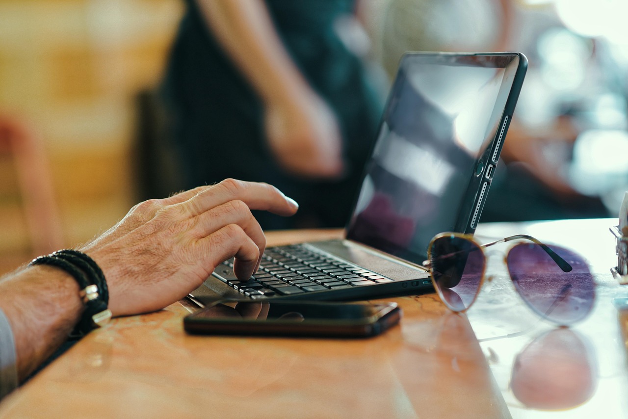 Persoon typt op een laptop toetsenbord aan een bureau